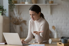 Irritated Woman Sit At Table Staring At Laptop Screen Feels Angry And Confused Having Problems With Broken Computer, Reading Message With Bad News In Email, Lost Information, Apps Malfunction Concept