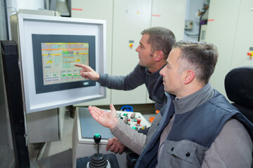 two men talking and sitting in the control room