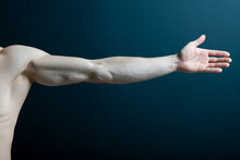 Crop Muscular Hand Of Faceless Male With Arm Stretching On Dark Background.