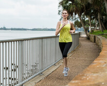 United States, Florida, Tampa, Woman Jogging On Footpath By River
