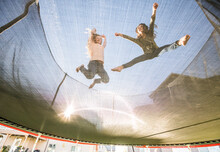Low Angle View Of Sisters (10-11, 12-13) Jumping On Trampoline