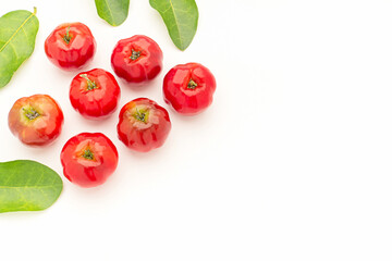 Wall Mural - Pile of ripe red acerola cherries and green leaves on a white background