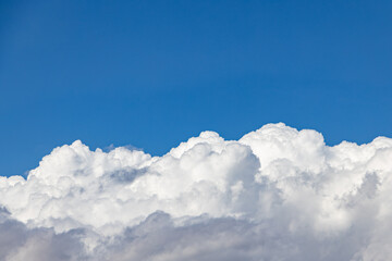 thick white cummulus clouds on a sunny day against a bright blue sky. 
absorbent cotton clouds indicating bad weather. blue background on a sunny day. 