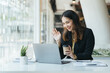 © PaeGAG - Happy young indian business woman entrepreneur using computer looking at screen working in internet sit at office desk, smiling hindu female professional employee typing email on laptop at workplace
