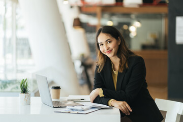 Young asian woman using computer laptop. looking at the camera with showing success.