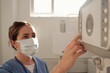© pressmaster - Young nurse pushing button on control panel of x-ray equipment while preparing for radiological examination of patients