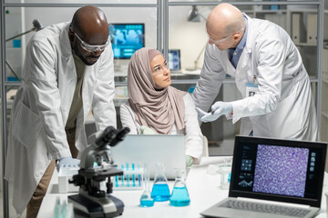 Aufkleber - Young contemporary clinicians or scientists in lab coats and protective eyewear consulting about new scientific research at meeting
