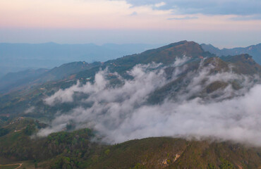 Aerial top view of forest trees and green mountain hills with fog, mist and clouds. Nature landscape background, Thailand.