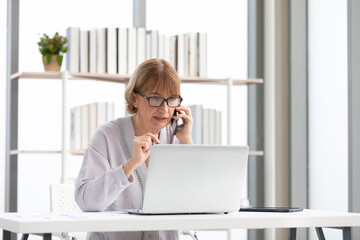 Wall Mural - senior businesswoman or freelance using laptop computer and talking about work on phone