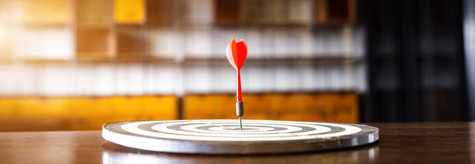 Wall Mural - Red dart arrow hitting in the target center of dartboard on bullseye with sun light vintage style, Target marketing and business success concept