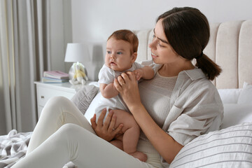 Wall Mural - Young woman with her little baby on bed at home