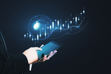 Poster - Close up of businessman hand holding tablet with glowing candlestick forex chart hologram on dark background. Trade and technology concept.
