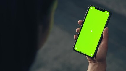 back view of fitness woman using green screen smart phone at home. Woman preparing for workout using smart phone.Woman using mobile phone while resting during fitness training