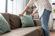 household, home improvement and cleaning concept - close up of woman arranging cushions on armchair and sofa