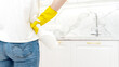 © I - Beautiful woman in protective gloves cleaning kitchen cabinet