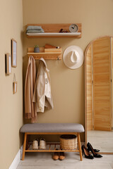 Hallway interior with stylish furniture, accessories and wooden hanger for keys on beige wall