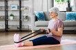 © Syda Productions - sport, fitness and healthy lifestyle concept - smiling senior woman exercising with resistance band on mat at home