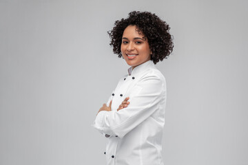 cooking, culinary and people concept - happy smiling female chef in white jacket over grey background