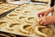 Hände von Bäcker legen Croissants auf ein Backblech