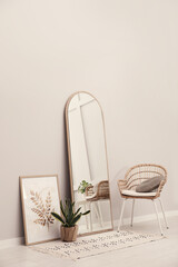 Sticker - Beautiful mirror, armchair and plant near white wall indoors. Interior design