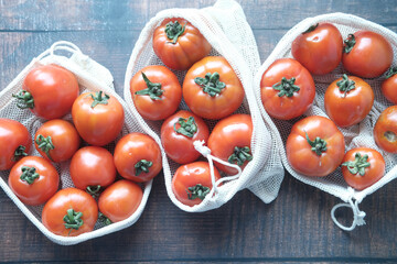 fresh Tomatoes in a reusable shopping bag on table 