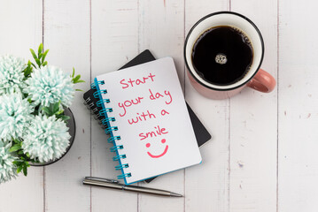 Wall Mural - Start your day text with a smile on note pad with a cup of coffee and flower - flat lay