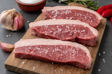 Sliced raw picanha or rump meat over wooden board with seasonings