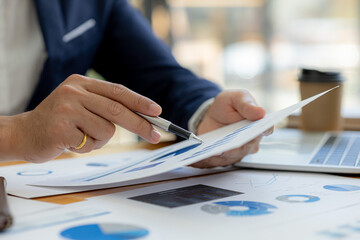 Business man pointing to a chart document showing company financial information, He sits in her private office, a document showing company financial information in chart form. Financial concepts