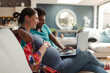 © Caia Image - Pregnant couple using laptop on living room sofa