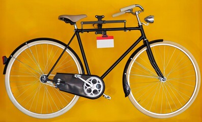 Classic vintage black bicycle for man on display. Yellow background.