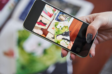 Wall Mural - Female graphic designer holding smartphone and shooting her art works