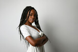 Profile photo of young African woman with long braids posing over white wall.