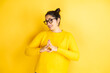 Young beautiful woman wearing casual sweater over isolated yellow background with Hands together and fingers crossed smiling relaxed and cheerful. Success and optimistic