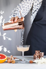 Wall Mural - Real woman preparing Pink Lychee Cocktail in Champagne coupe glass surrounded by ingredients and bar tools