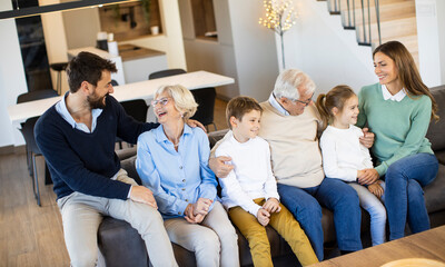 Wall Mural - Multi generation family sitting together on the sofa at home and watching TV