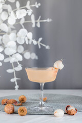 Wall Mural - Pink Lychee Cocktail. Champagne coupe glass filled with pink lychee cocktail or mocktails surrounded by ingredients and bar tools