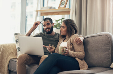 Poster - A happy customer is a comfortable customer. Shot of a young couple using a laptop and credit card on the sofa at home.