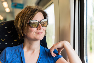 Zellik, Flemish region - Belgium - Attractive thirty year old woman with sunglasses looking out of the window of a local train