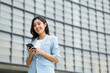 © Chanakon - Beautiful business woman using mobile phone to play social media in the buildings at downtown. Smart female using cell phone chatting for business communication. Smartphone concept.