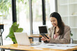 © PaeGAG - Happy young Asian businesswoman using smartphone at office.