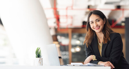 Young asian beautiful and charming businesswoman smiling and working on laptop computer at office.