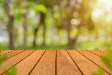 Empty wooden top table in front of blurred beautiful big tree in the forest with natural sunlight and bokeh background with copy space. Can be used for display or montage for show your product.