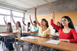 © CarlosBarquero - Multi-ethnic students in class with hands raised. Concentrated young people with serious faces answering the teacher's question.