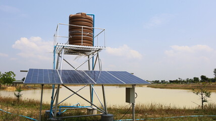 Wall Mural - Solar panels and water tanks. Close-up of photovoltaic cells for generating electric power to feed a water pump motor in a smart farm pool with copy space. Selective focus