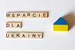 Wsparcie humanitarne dla Ukrainy - napis z literek obok drewnianego domku