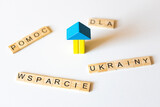 Fototapeta Dmuchawce - Pomoc wsparcie dla Ukrainy - słowa z literek przy drewnianym domku w barwach narodowych Ukrainy