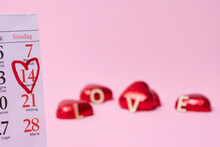 Heart-shaped Candies And Calendar On Pink Background