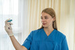 © RomanR - beautiful young nurse in uniform and gloves holding a vaccine.