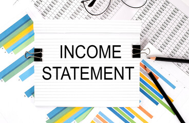 Poster - Notebook with pencils, glasses on graph background, with text INCOME STATEMENT