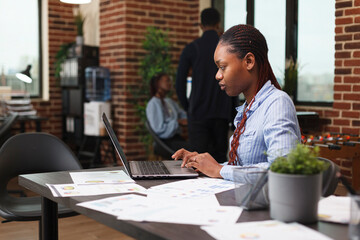 Poster - Confident african american business woman analyzing project financial statistics. Business company manager working on management plan and marketing strategy while in modern office.